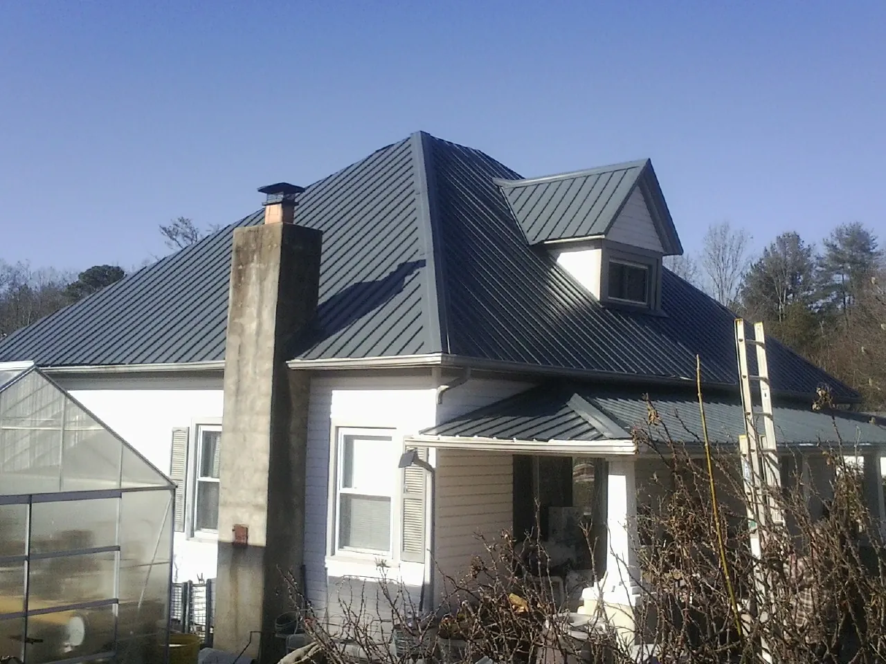 Dark blue standing seam metal roof on a white farmhouse with dormer — Slate & Tile Roof Repair by Roofing Brothers in Mcloud