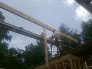 Carpenter setting a ridge beam over a new addition frame — Ice Dam Removal by Roofing Brothers in Mcloud