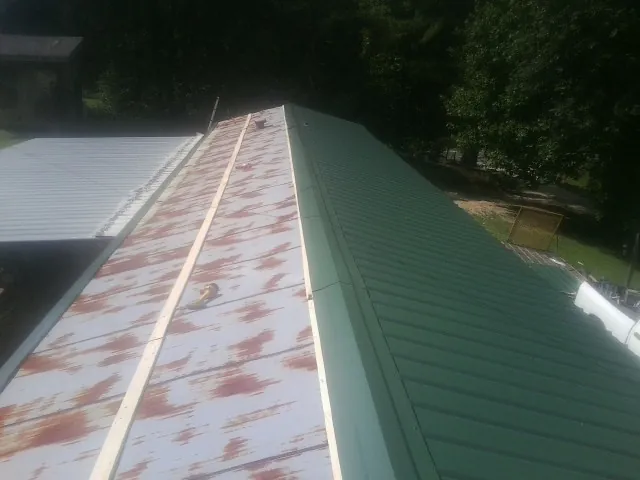 Old rusted panels beside newly installed green metal roofing — Wind Damage Roof Repair by Roofing Brothers in Mcloud