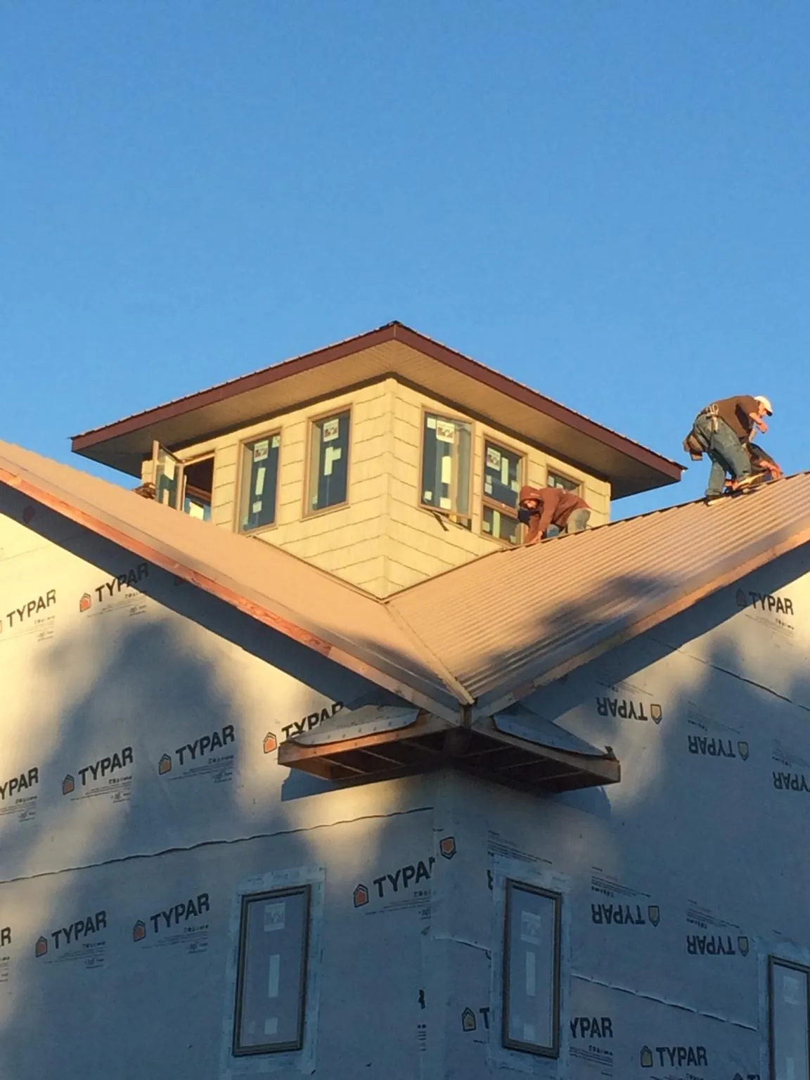 Roofers working around a rooftop cupola on a new metal roof at sunset — Roof Waterproofing in Mcloud by Roofing Brothers